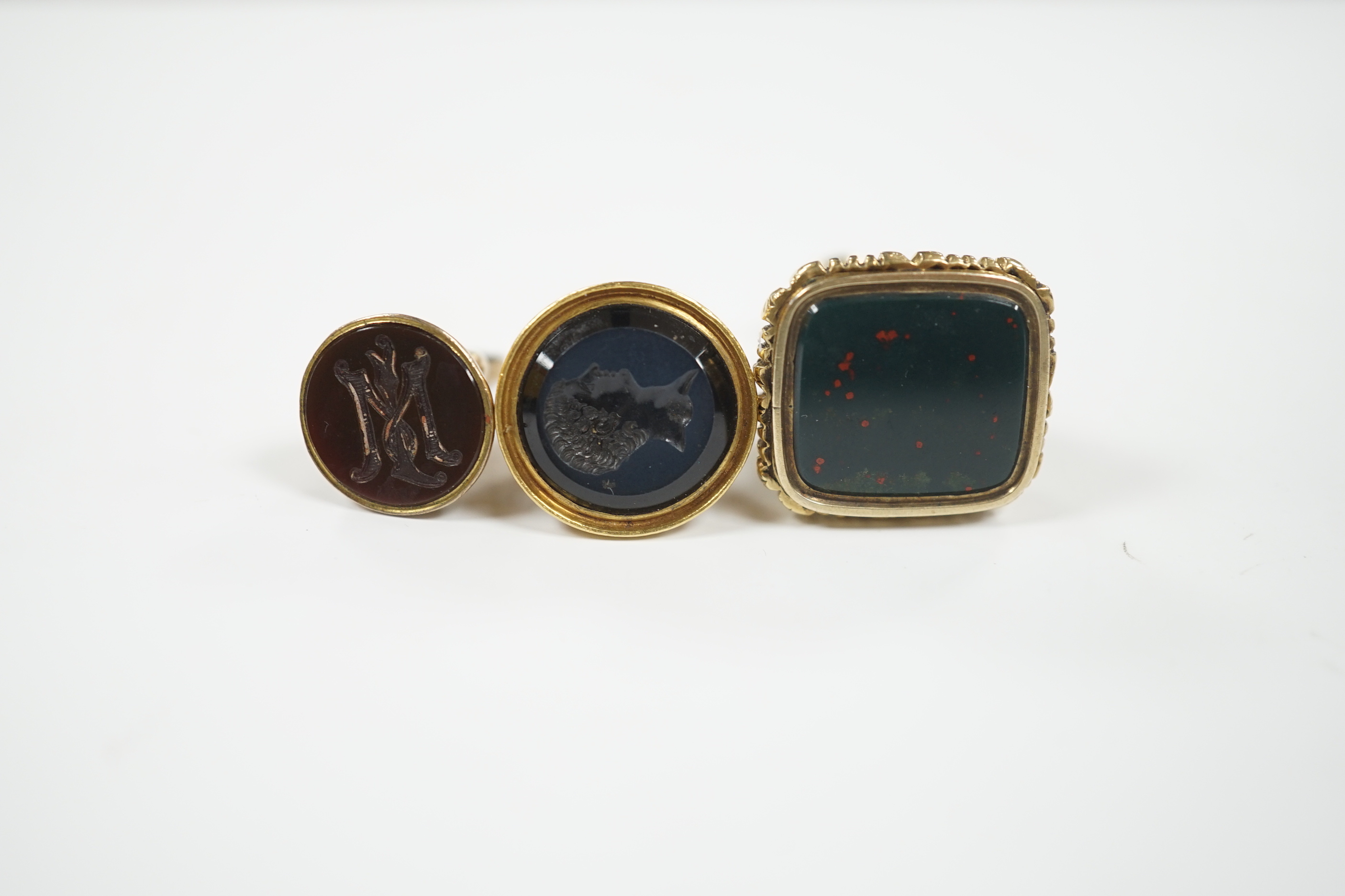 Three assorted Victorian and later yellow metal overlaid and chalcedony set fob deals, including intaglio bust of a gentleman, largest 35mm.